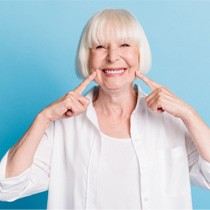 Woman smiling and pointing to dentures