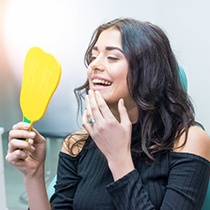 woman seeing her smile in a mirror in dental chair