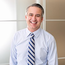 smiling man wearing a tie and standing in an office