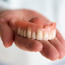 A hand holding a denture