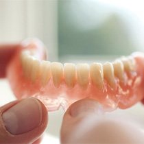 A closeup of two hands holding a bottom denture