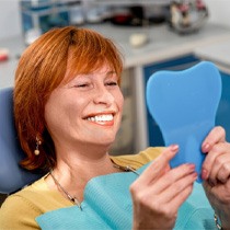 A senior woman admiring her smile in the dentist’s office