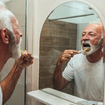 Man practicing dental implant care in Astoria by brushing