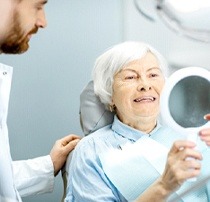 elderly woman admiring her smile in the mirror 