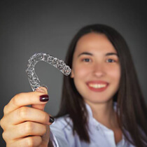 Woman holding Invisalign tray