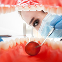 A woman examining the inside of a person’s mouth.