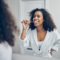 woman brushing her teeth to prevent dental emergencies in Astoria 
