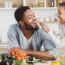 little kid giving their father a cherry tomato 