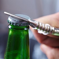person using a bottle opener on a green glass bottle 