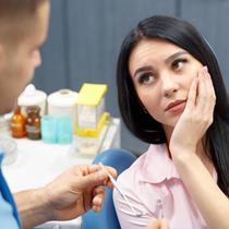 Woman in dental chair holding cheek