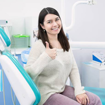 Woman in dental chair giving thumbs up