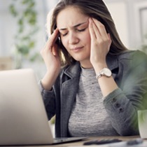 Woman holding her temples at work