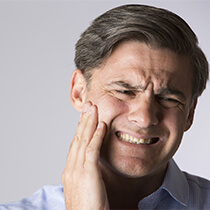 Man in pain holding teeth