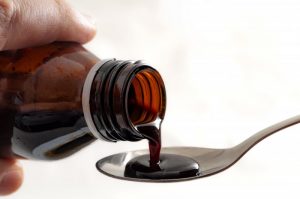 person pouring cough syrup into a spoon