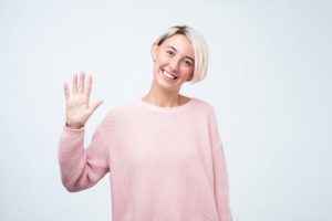 Smiling woman waving to her Astoria dentist in COVID-19