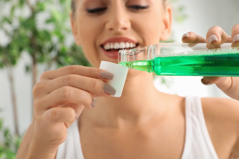 Woman pouring mouthwash into bottle cap