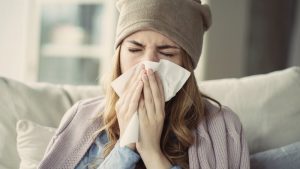 woman blowing her nose during cold and flu season in Astoria 