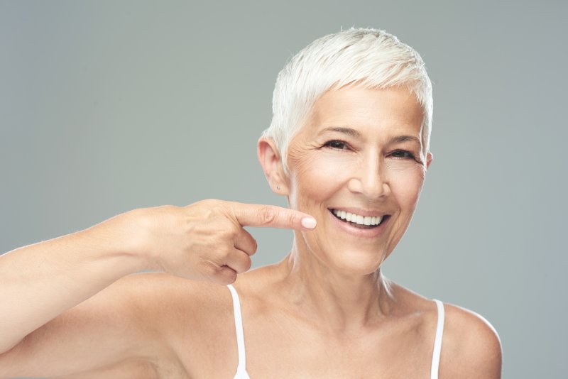 woman pointing to her dental implants in Astoria