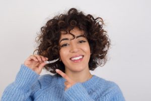 young woman holding Invisalign aligner