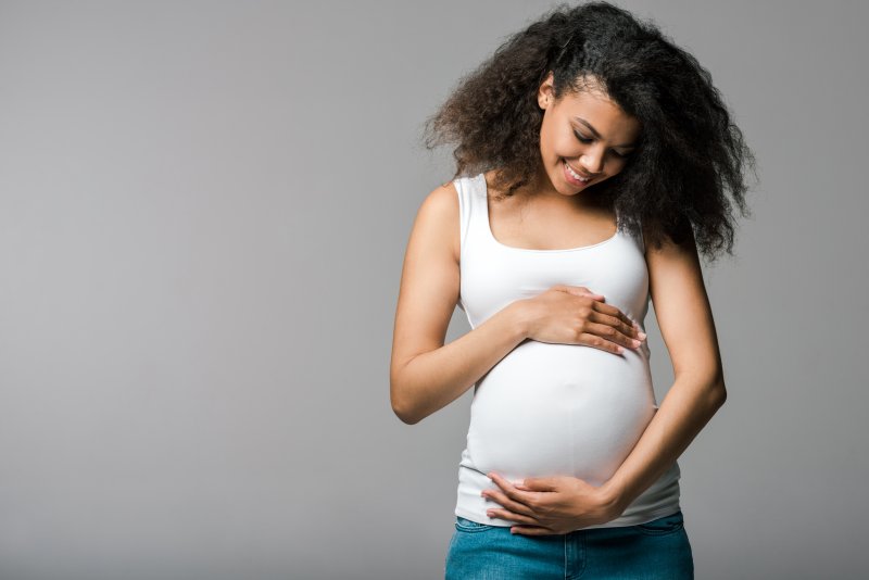 young pregnant woman smiling and holding belly