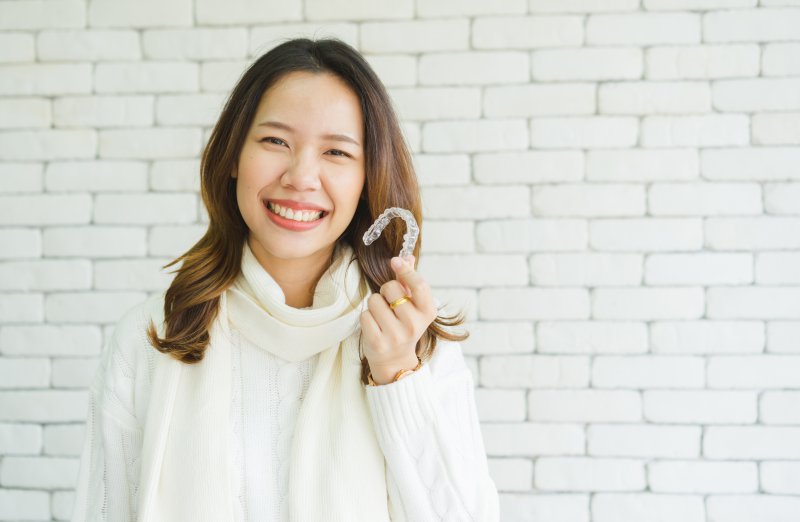 Woman holding Invisalign tray.