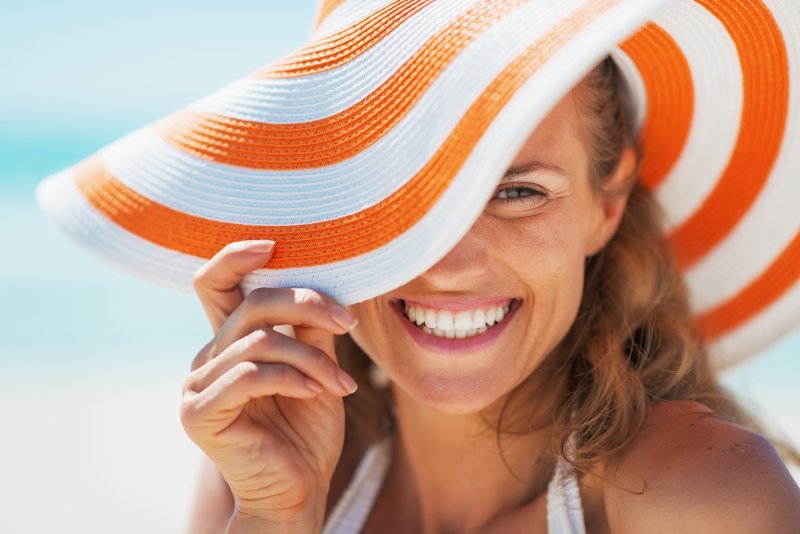 Woman smiling and wearing beach hat.