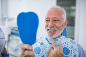 man seeing his smile in a dental mirror