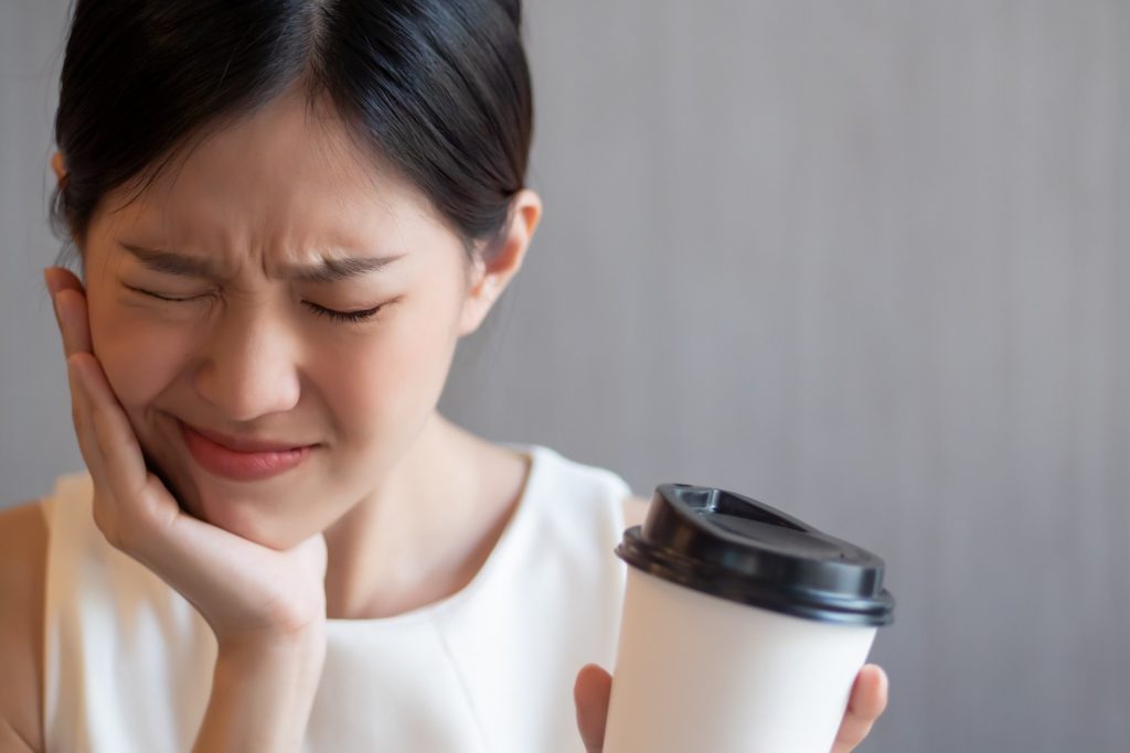 Woman experiencing sensitivity to hot coffee