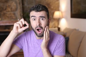 a man shocked and holding the tooth that he lost