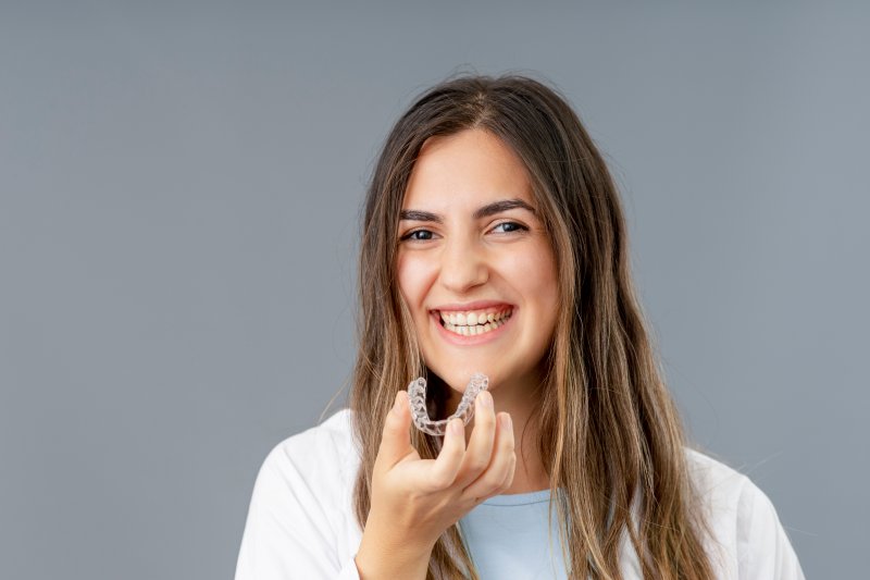 Young woman holding up an Invisalign aligner