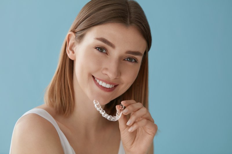 Young woman holding their Invisalign aligner