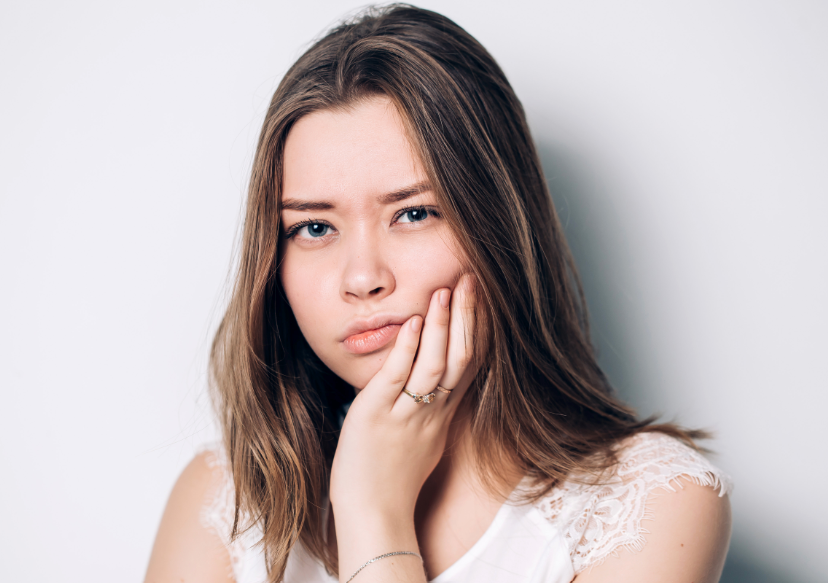 Girl holding jaw looking miserable