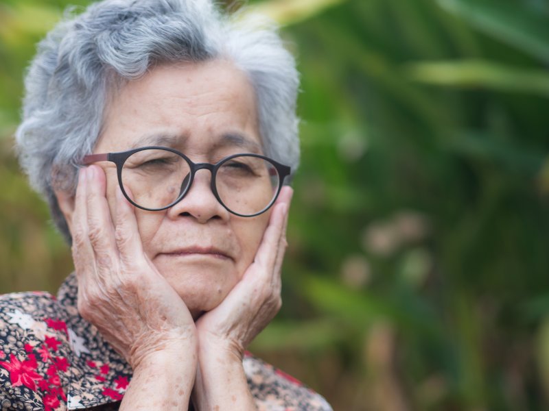 An older woman experiencing pain from denture sores